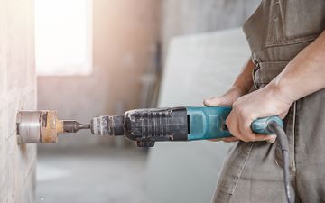 Arbeiter von Erdbau Holzinger-Gruber führt Kernbohrung an Wand in Amstetten durch